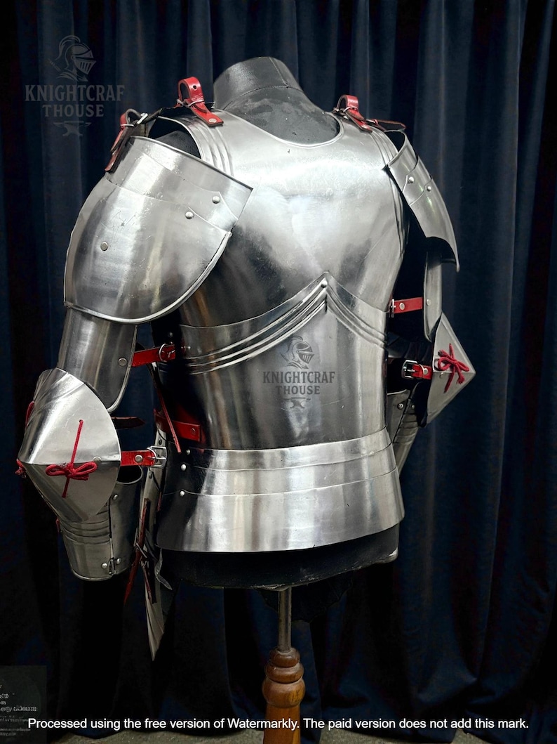 May include: A polished, silver-colored suit of armor, featuring shoulder and arm protection, a chest plate, and a waist guard. Red leather straps and accents are visible. The text "KNIGHTCRAF THOUSE" is printed on the armor.