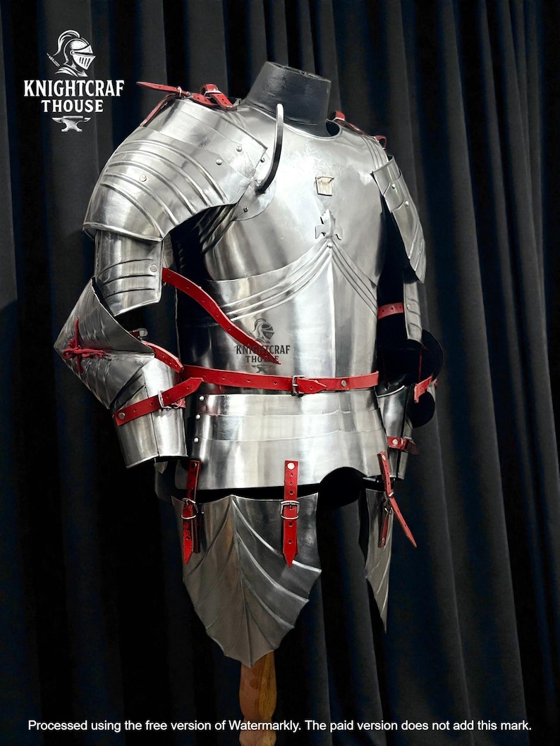 May include: A full suit of polished steel armor with red leather straps and accents. The armor is displayed on a mannequin, showcasing its intricate design and craftsmanship. The image includes the text "KNIGHTCRAF THOUSE".