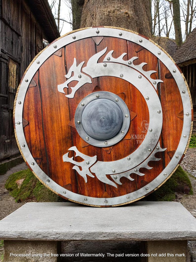 May include: A round wooden shield with a metal rim and a silver dragon design. The shield has a small metal boss in the center.