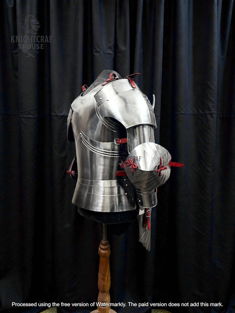 May include: A polished steel breastplate and arm armor with red leather accents. The armor is displayed on a mannequin against a black backdrop. The image includes the text "KNIGHTCRAFT HOUSE".