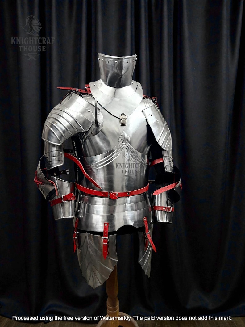May include: A full suit of polished steel armor with red leather straps and accents. The armor includes a helmet, chest plate, shoulder guards, arm and leg protection. The Knightcrafthouse logo is visible. The armor is displayed on a wooden stand.