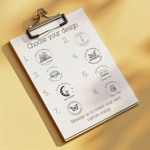 May include: A white sheet of paper with a clipboard attached to the top. The paper has a list of eight different bookplate designs with the text "Choose your design" at the top. Each design features a book, flowers, and a name. The text "Message us to create your own custom stamp" is at the bottom of the page.