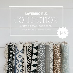 May include: A collection of eight rolled-up rugs with various black and white, gray, and brown geometric patterns. The text "LAYERING RUG COLLECTION 8 STYLES TO CHOOSE FROM (CLICK THE LINK IN THE DESCRIPTION) $15" is displayed above the rugs.