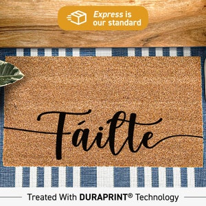 May include: A brown coir doormat with the word "Fáilte" written in black cursive script. The doormat is treated with DURAPRINT technology.