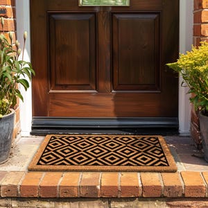May include: A brown doormat with a black geometric pattern. The doormat is placed in front of a wooden door with a black trim.