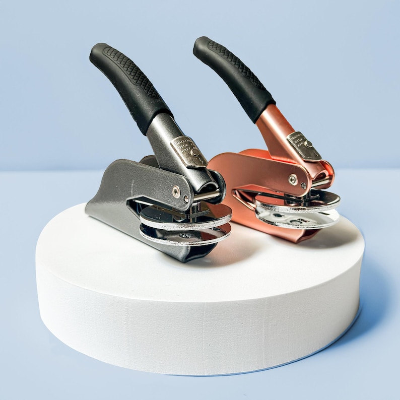 May include: Two metal self-inking stamps with black handles. One stamp is silver and the other is rose gold.