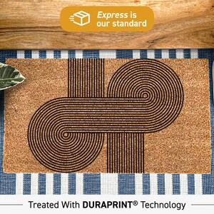 May include: A brown coir doormat with a geometric design of overlapping circles and lines. The doormat has the text "Treated With DURAPRINT® Technology" printed on the bottom.