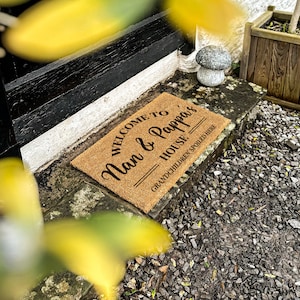 Puede incluir: Una alfombra de coco marr&oacute;n con el texto "Welcome to Nan & Pappa's House - Grandchildren Spoiled Here" impreso en negro.