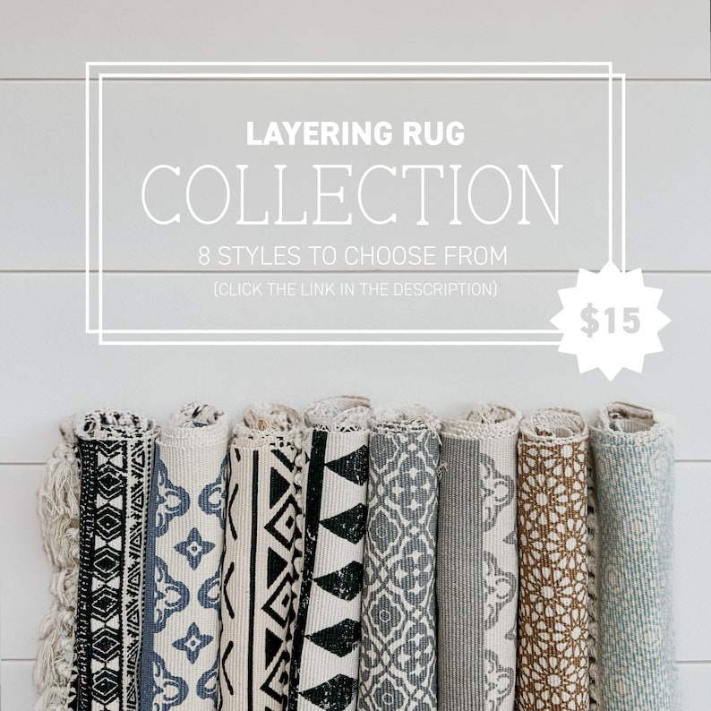 May include: A collection of eight rolled-up rugs with various geometric patterns in black, white, and blue. The rugs are displayed against a white wood background. The text "LAYERING RUG COLLECTION 8 STYLES TO CHOOSE FROM (CLICK THE LINK IN THE DESCRIPTION) $15" is displayed above the rugs.