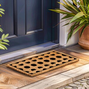 a door mat on the ground next to a potted plant