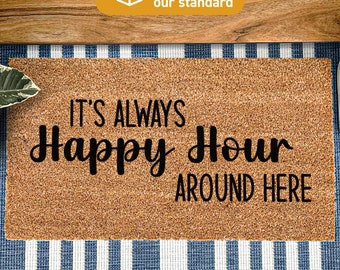 May include: A brown coir doormat with the text "It's Always Happy Hour Around Here" in black lettering. The doormat is on a blue and white striped surface.