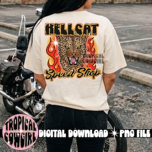 Może przedstawiać: Kremowy t-shirt z grafiką na plecach z napisem HELLCAT SPEED SHOP w kolorze czarnym i pomarańczowym. Wzór przedstawia głowę lamparta z zielonymi oczami, umieszczoną centralnie na tle pomarańczowych i żółtych płomieni z białymi gwiazdkami.
