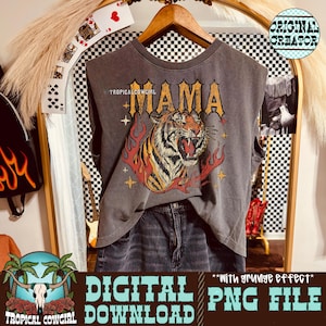 Puede incluir: Camiseta sin mangas gris con un gráfico de tigre y la palabra "MAMA" en letras doradas. La camiseta también tiene el texto "TROPICALCOWGIRL" y "DIGITAL DOWNLOAD PNG FILE". La camiseta está colgada en una percha de madera.