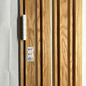 May include: Six wooden tile racks for playing dominoes or mahjong. The racks are made of light brown wood with a natural grain pattern.  A set of dominoes is shown in the image, including a joker tile and tiles with the numbers 2 and 3.
