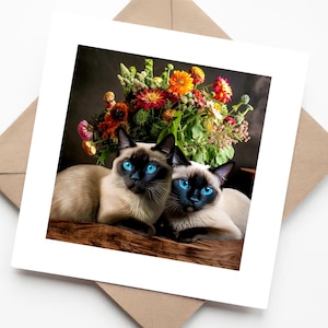 Deux chats siamois aux grands yeux bleus assis ensemble sur une table avec une composition florale - Carte de voeux de luxe faite main chat mignon