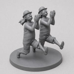 May include: A grayscale sculpture of two figures in matching outfits, each wearing a bowler hat and shorts. They are in a running pose with their hands clasped together. The sculpture is mounted on a circular base.