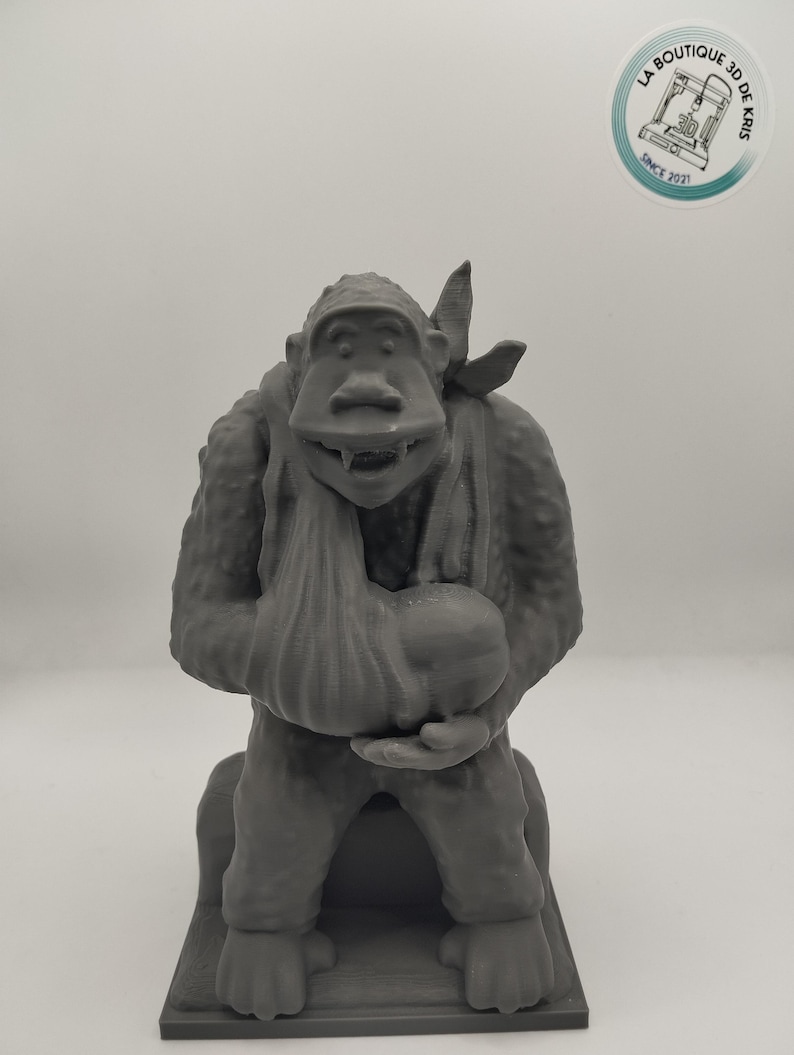 May include: A gray 3D printed figurine of a monkey holding a bag. The monkey is wearing a bandana and has a mischievous expression.