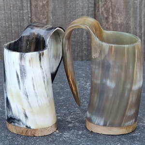 Peut inclure: Deux tasses &agrave; boire en corne brune et blanche avec des bases en bois. Les tasses ont un aspect unique, naturel et rustique.