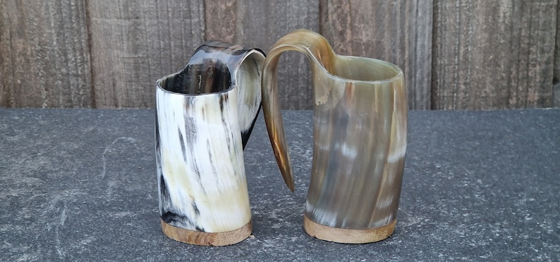 Peut inclure: Deux tasses &agrave; boire en corne brune et blanche avec des bases en bois. Les tasses ont un aspect unique, naturel et rustique.