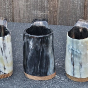 "Image of a Viking horn mug with handle in three distinctive colors: white, pale beige, and deep black. The mug measures approximately 3-4 inches in height."