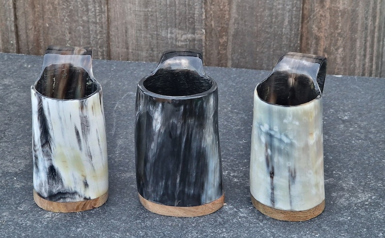 "Image of a Viking horn mug with handle in three distinctive colors: white, pale beige, and deep black. The mug measures approximately 3-4 inches in height."