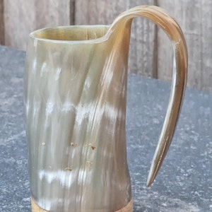Peut inclure: Une tasse &agrave; boire en corne brune et blanche avec une base en bois. La tasse a un motif naturel unique et une poign&eacute;e incurv&eacute;e.