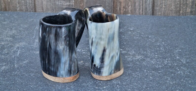 Peut inclure: Deux mugs en corne noire et blanche avec des bases en bois. Les mugs sont faits de corne naturelle et ont un aspect rustique unique.
