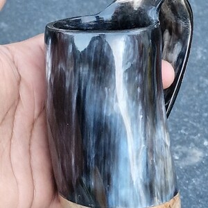 Peut inclure: Une tasse &agrave; boire en corne noire et blanche avec une base en bois. La tasse a un motif en spirale unique.