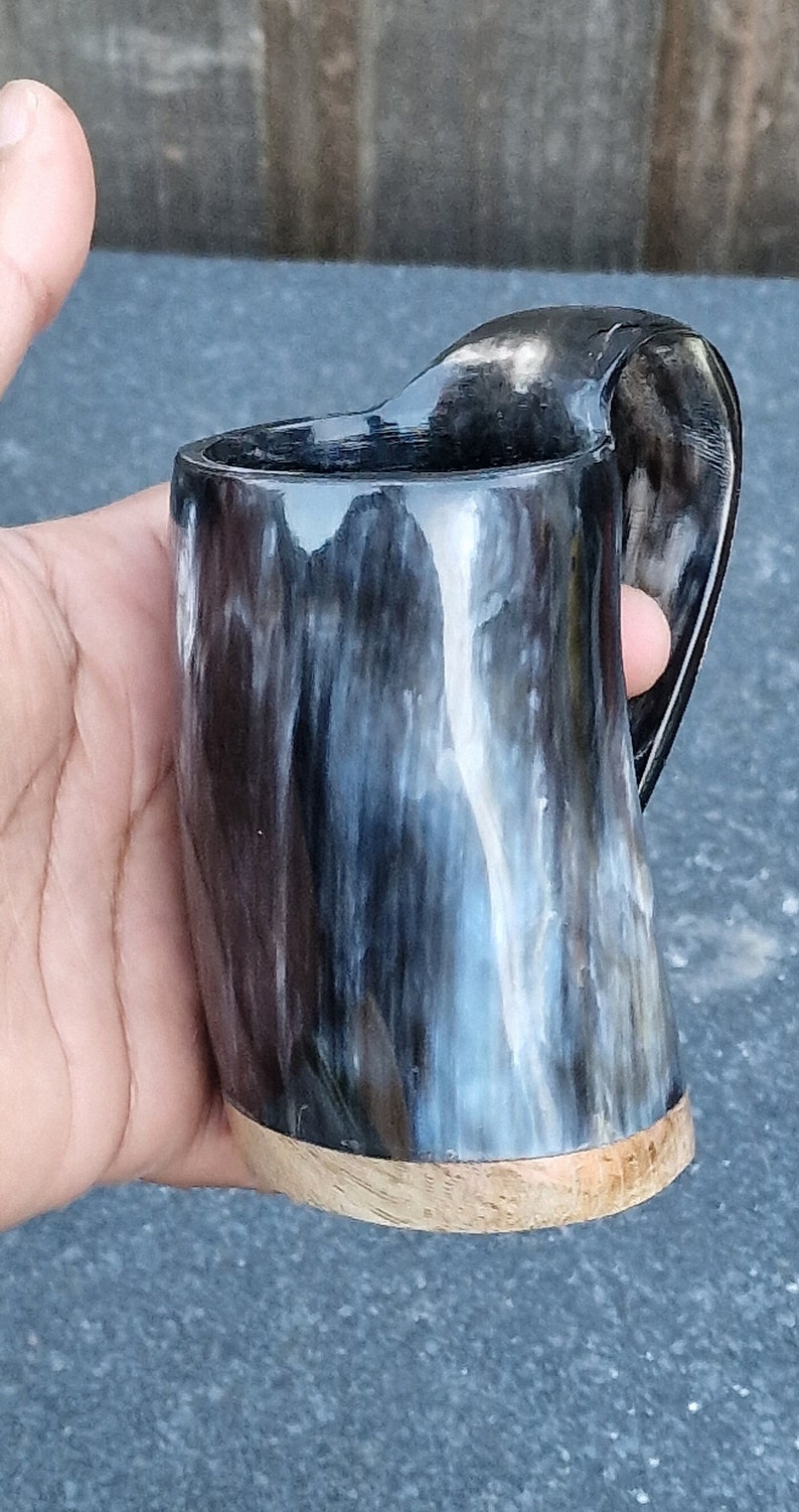 Peut inclure: Une tasse &agrave; boire en corne noire et blanche avec une base en bois. La tasse a un motif en spirale unique.