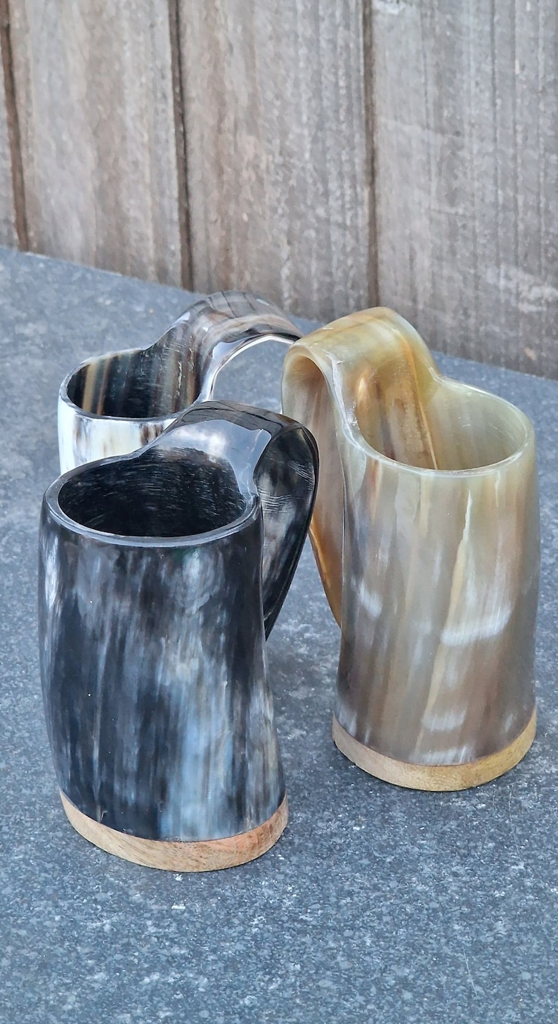 Peut inclure: Trois cornes &agrave; boire en corne polie avec des bases en bois. Les cornes sont de diff&eacute;rentes nuances de brun, noir et blanc.