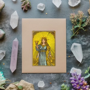 May include: A tarot card with a gold frame and a woman holding a golden chalice. The woman is wearing a blue robe and a crown. The background is yellow with a sunburst design.