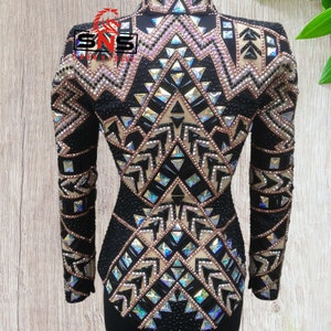 May include: Black show shirt with a geometric pattern of gold, black, and iridescent rhinestones. The shirt has long sleeves and a high collar.