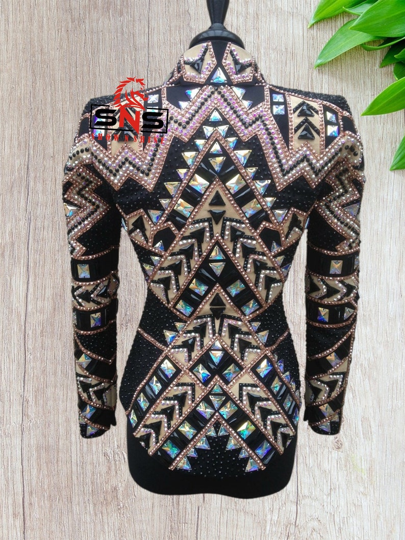 May include: Black show shirt with a geometric pattern of gold, black, and iridescent rhinestones. The shirt has long sleeves and a high collar.