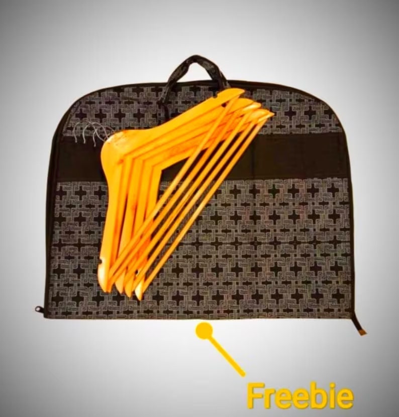 May include: A black garment bag with a geometric pattern and a zipper closure. The bag is filled with a stack of wooden hangers.