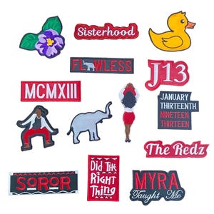 Może przedstawiać: Kolekcja kolorowych, haftowanych naszywek z różnymi wzorami i tekstami. Wzory obejmują żółtą kaczkę, fioletowy kwiat, słonia oraz słowa "Sisterhood", "Flawless" i "The Redz".