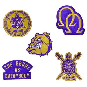 May include: A selection of purple and gold embroidered patches. The designs feature a bulldog, Greek letters, shields, swords, and the text "THE BRUHZ -VS- EVERYBODY". These patches are likely for clothing or accessories.