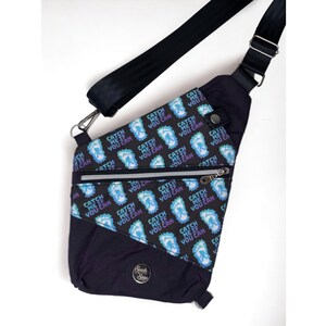 May include: A black crossbody bag with a zippered pocket and a strap. The bag is covered in a repeating pattern of blue and purple footprints with the text "Catch Me If You Can".