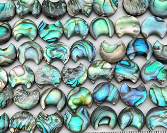 May include: A collection of iridescent abalone shell half-moon shaped beads. The beads are a mix of green, blue, and purple colors.