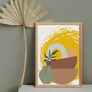 May include: A framed print with an abstract design featuring a yellow sun, a brown bowl, and a green vase with a small plant. The background is a white canvas with a yellow brushstroke.