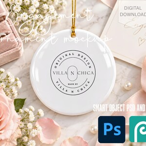 May include: A white circular ceramic ornament with a gold hanging string. The center features a black circular logo with the text "ORIGINAL DESIGN VILLA N CHICA MADE BY VILLA N CHICA". The ornament is displayed alongside a ring box and text.