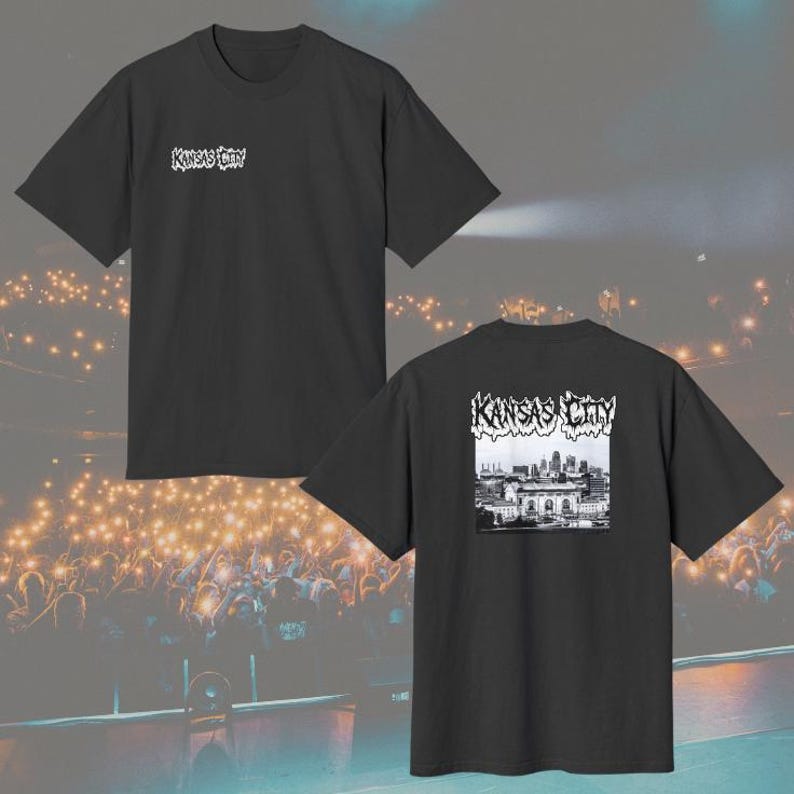 May include: A black short-sleeve t-shirt featuring the text Kansas City in a stylized white font on the upper left chest. The back of the shirt displays a black and white graphic of the Kansas City skyline with the text Kansas City above it.
