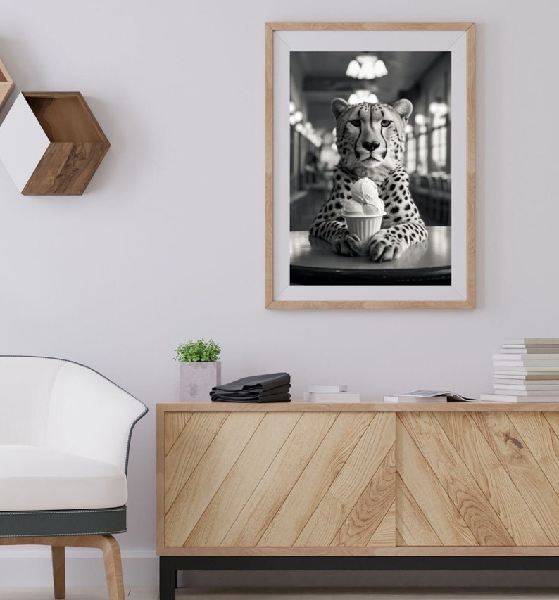 Puede incluir: Una fotograf&iacute;a en blanco y negro de un guepardo sentado en una mesa con una taza de helado. El guepardo est&aacute; mirando directamente a la c&aacute;mara.