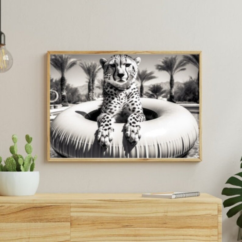 May include: A black and white photograph of a cheetah sitting in a white inflatable ring. The cheetah is looking at the camera with a serious expression. The ring is floating in a pool of water. Palm trees are in the background.