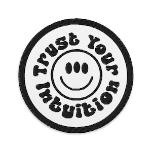 May include: White round patch with black stitching and a black smiling face with three dots for eyes. The text "Trust Your Intuition" is written around the face in a black, stylized font.