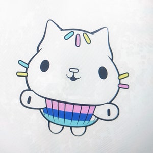 Op de afbeelding: Een witte cartoonkat met zwarte ogen en een roze en blauwe gestreepte trui. De kat heeft gele en roze sprinkels op zijn hoofd.