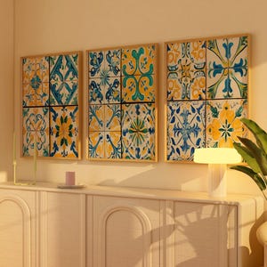 Op de afbeelding: Drie ingelijste prints van kleurrijke tegelpatronen in tinten blauw, geel en groen. De prints hangen aan een lichtbeige muur boven een wit kastje.