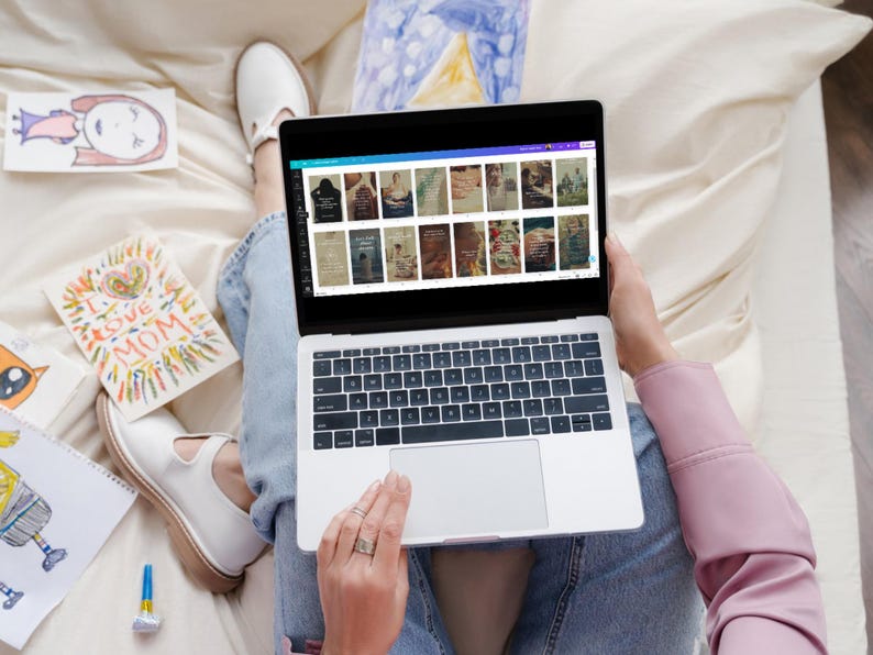 May include: A person sitting on a white couch using a laptop computer. The laptop screen shows a website with multiple images of different designs. The person is wearing blue jeans and a pink shirt.