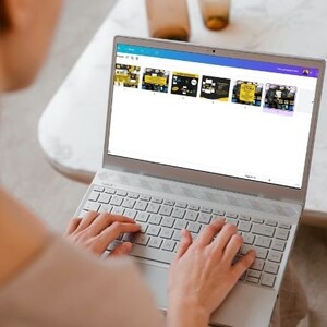 May include: A person is using a laptop computer with a white keyboard. The laptop screen displays a web page with several colorful squares. The squares contain images and text.