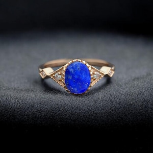 Op de afbeelding: Een ring van roségoud met een blauwe ovale edelsteen en kleine diamanten op de band.