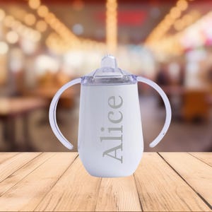 A custom engraved 10oz stainless steel sippy cup featuring double-walled insulation, a spill-proof Triton lid, and a BPA-free design. Available in White, Green, Pink, and Blue, this personalized baby cup is perfect for toddlers.